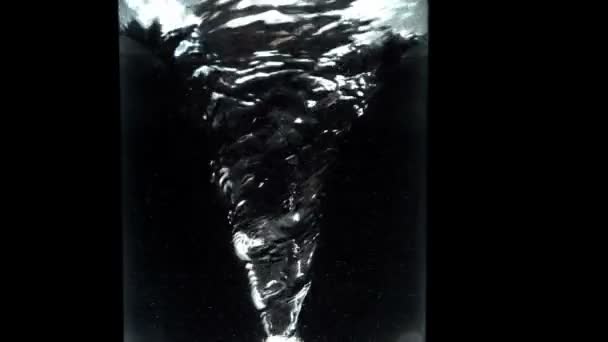 Tourbillon dans un verre d'eau sur fond noir gros plan — Video