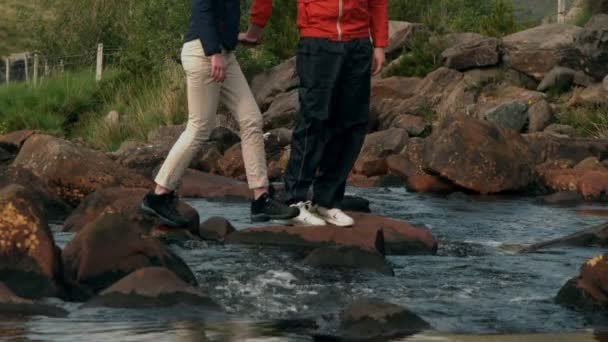 Couple crossing a stream together in the countryside — Stock Video