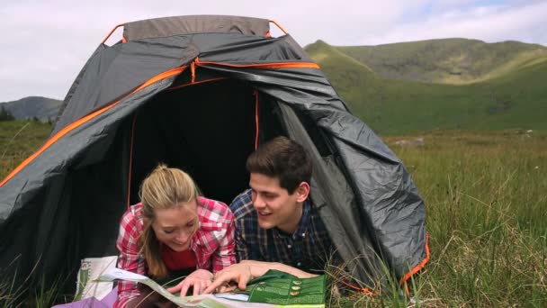Glückliches Paar liest Landkarte liegend im Zelt — Stockvideo