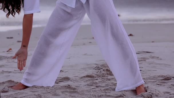 Kvinna utövar yoga och stretching på stranden — Stockvideo