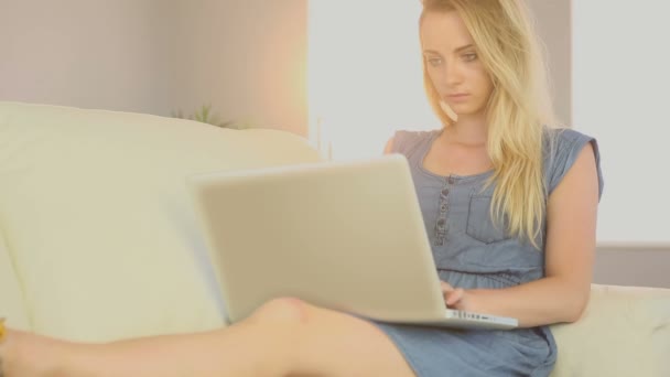 Gyönyörű tini használ laptop lány a kanapén — Stock videók