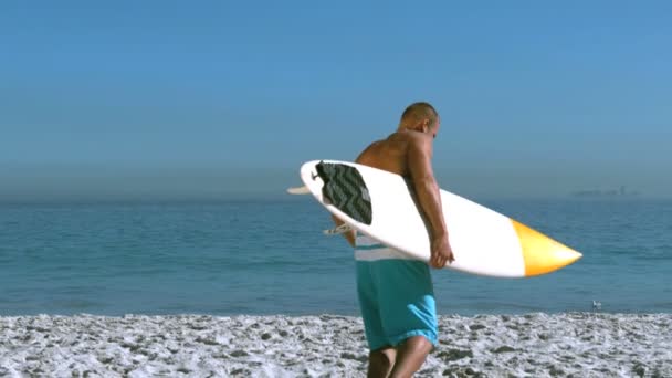 Bell'uomo con una tavola da surf che corre in mare — Video Stock