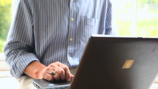 Gericht volwassen man zit door een venster met behulp van zijn computer — Stockvideo