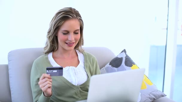 Verheugd vrouw haar creditcard bedrijf en met behulp van haar laptop — Stockvideo