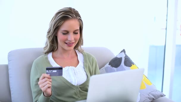 Femme ravie tenant sa carte de crédit et utilisant son ordinateur portable — Video