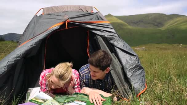 Paar liest Landkarte im Zelt liegend — Stockvideo