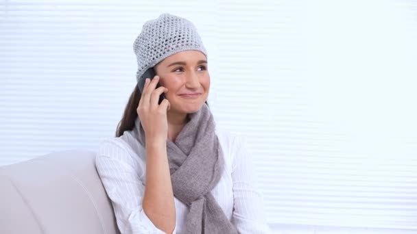 Mujer joven sonriente con sombrero y bufanda llamando a alguien — Vídeos de Stock
