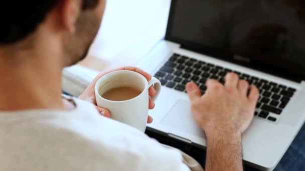 Człowiek pije kawę przy użyciu jego laptop — Wideo stockowe