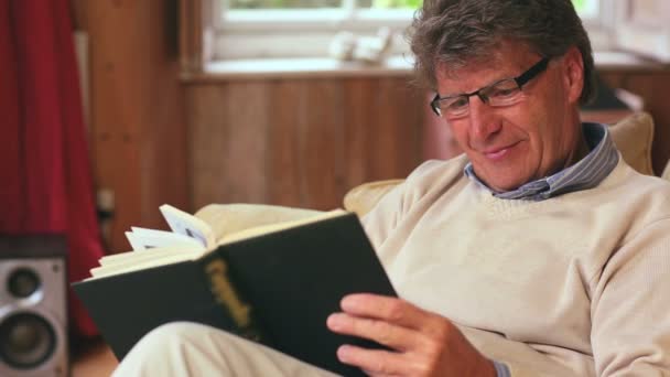 Mature man reading book while sitting — Stock Video