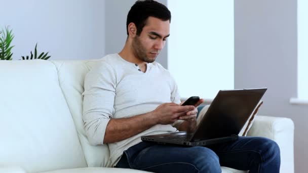 Homem usando seu smartphone e seu laptop — Vídeo de Stock