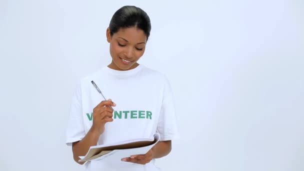 Mujer voluntaria sonriente pensando y escribiendo en un cuaderno — Vídeo de stock