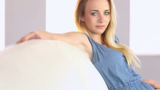 Hermosa rubia adolescente relajándose en el sofá — Vídeos de Stock