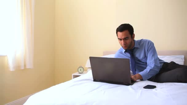 Empresário alegre digitando em seu caderno na cama — Vídeo de Stock