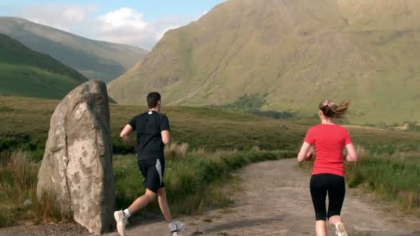 Man jogging and is met by his jogging girlfriend in the countryside — Wideo stockowe