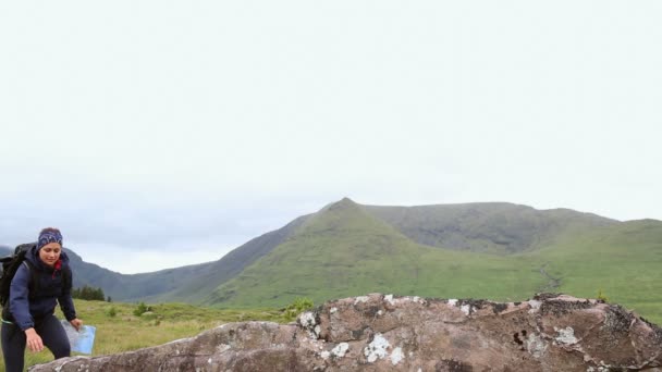 Mujer senderista llegando a la cumbre y mirando a su alrededor con un mapa — Vídeo de stock