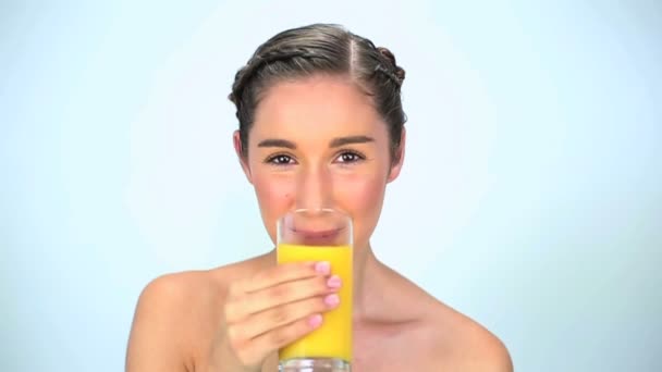 Молодая женщина пьет апельсиновый сок — стоковое видео