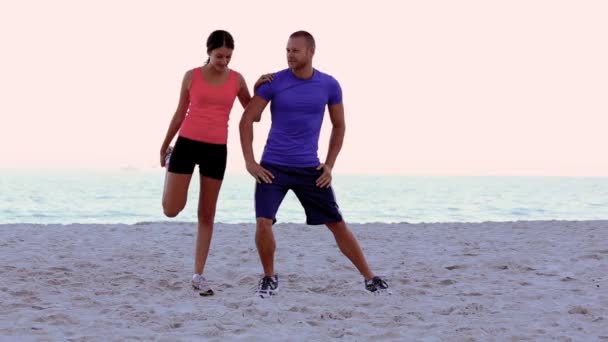 Kvinnan sträcker sig och bli coachad på stranden — Stockvideo
