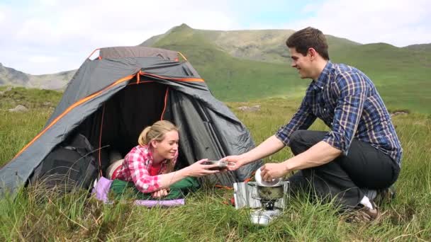 Hombre entregando a su novia un tazón de sopa en un viaje de campamento — Vídeos de Stock