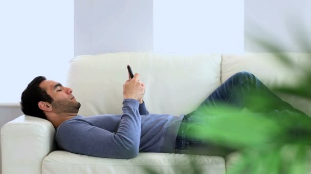 Hombre mensajes de texto acostado en el sofá — Vídeo de stock
