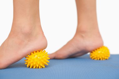 Female feet touching yellow massage ball clipart