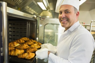 Mature baker smiling proudly at the camera clipart