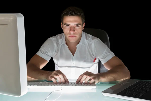 Handsome frowning computer engineer working at night — Stock Photo, Image