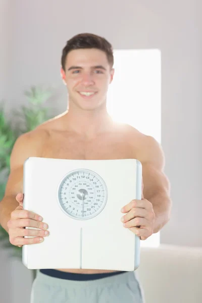 Homem bonito sorridente confiante mostrando escalas — Fotografia de Stock