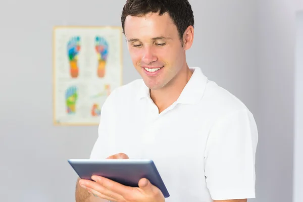 Handsome cheerful physiotherapist using tablet — Stock Photo, Image