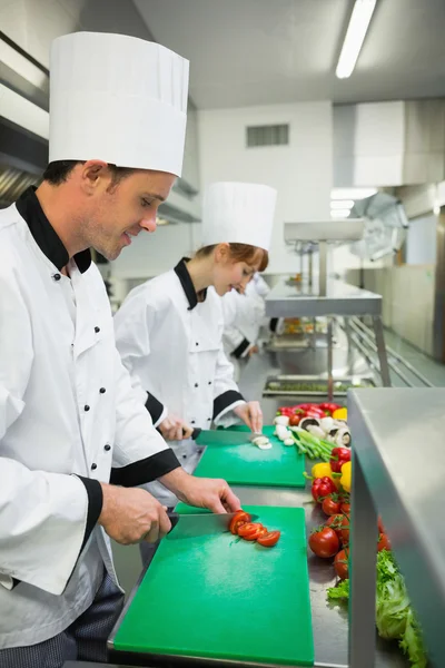 Twee jonge chef-koks snijden van groenten — Stockfoto