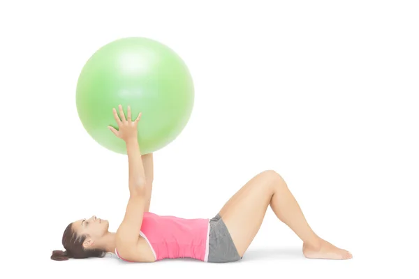 Attractive sporty brunette lying on floor holding exercise ball — Stock Photo, Image