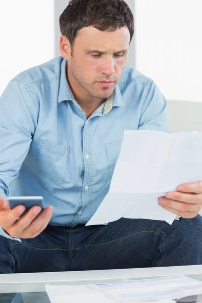 Hombre casual preocupado sosteniendo calculadora pagando facturas mirando el documento —  Fotos de Stock