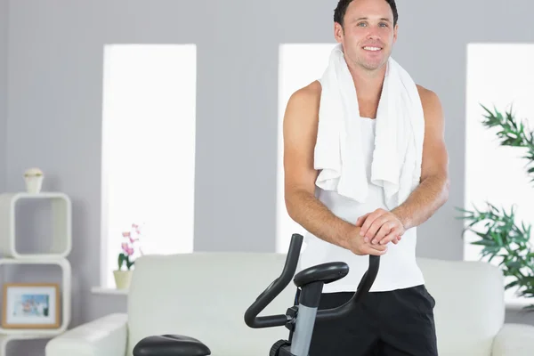 Smiling sporty man standing next to exercise bike — Stock Photo, Image