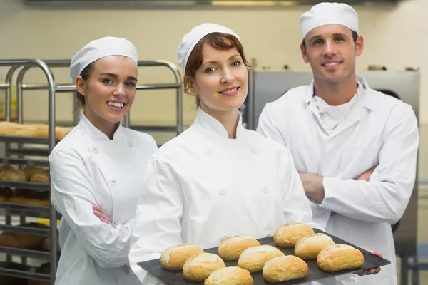 Drie jonge bakkers poseren in een keuken — Stockfoto