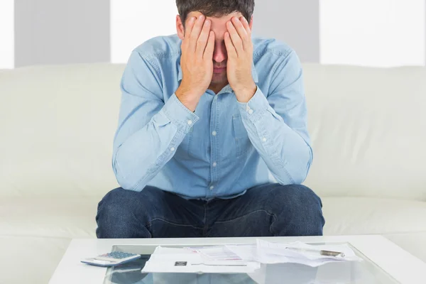 Onrustige casual man zittend op de bank die betrekking hebben op zijn ogen betalen van rekeningen — Stockfoto