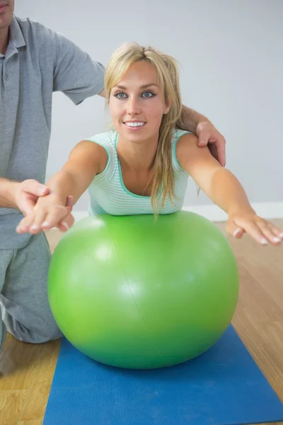 Physiotherapist holding patient doing exercise on exercise ball — Stock Photo, Image