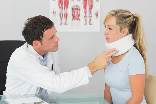 Atractivo médico examinando el cuello de un paciente — Foto de Stock