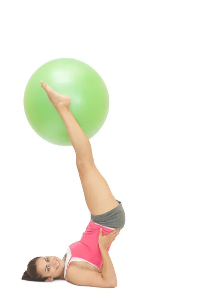 Sonriente morena deportiva sosteniendo pelota de ejercicio entre las piernas —  Fotos de Stock