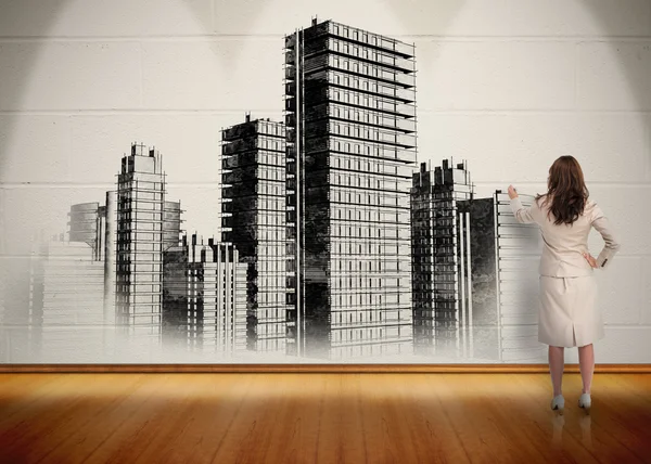 Businesswoman painting black and white city on wall — Stock Photo, Image
