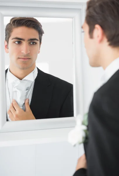 Novio joven serio enderezando su corbata — Foto de Stock