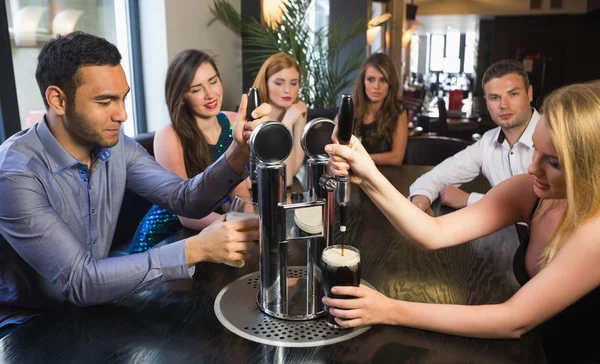 Friends sitting together and pulling pints — Stock Photo, Image