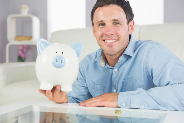 Bonito homem casual segurando porquinho banco — Fotografia de Stock