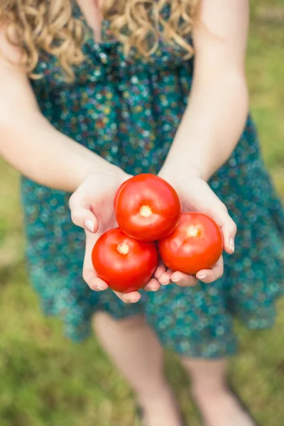 Mujer rubia sosteniendo algunos tomates — Foto de Stock