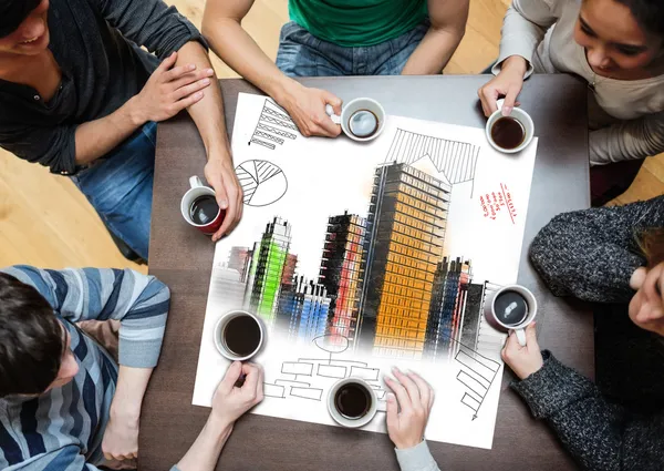 Overhead view of people sitting around table with painted city on sheet — Stock Photo, Image