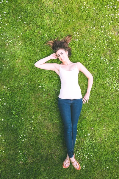 Ładny brunetka kobietę leżącą na trawnik — Stockfoto