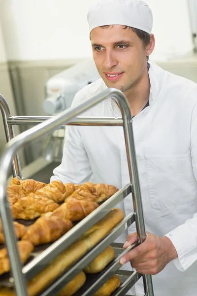 Handsome happy baker pushing a trolley — Stock Photo, Image