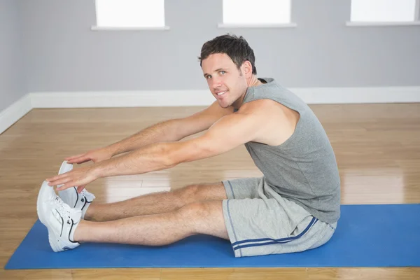 Sonriente hombre deportivo estirando sus piernas — Foto de Stock