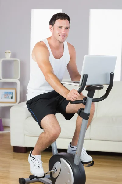 Ler sportig man utövar på cykel och hålla laptop — Stockfoto