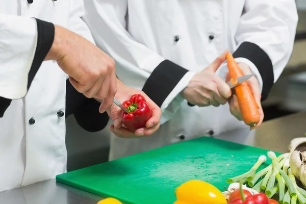 Närbild på två kockar skära grönsaker — Stockfoto