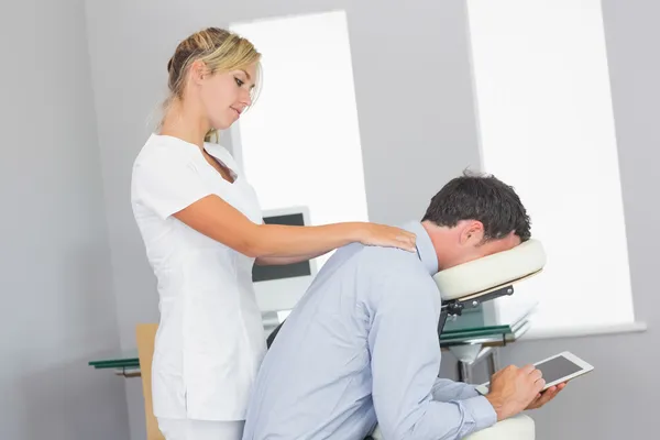 Masseuse massaging clients neck in massage chair — Stock Photo, Image