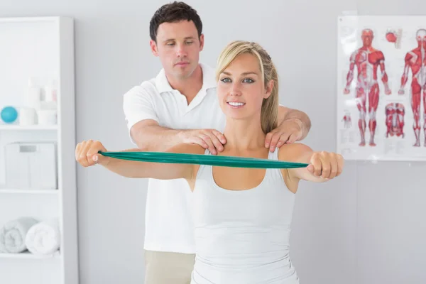 Handsome physiotherapist correcting position of patient — Stock Photo, Image